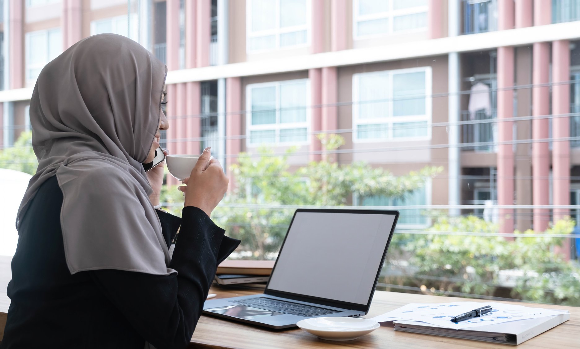 happy beautiful muslim female worker holding hot coffee mug